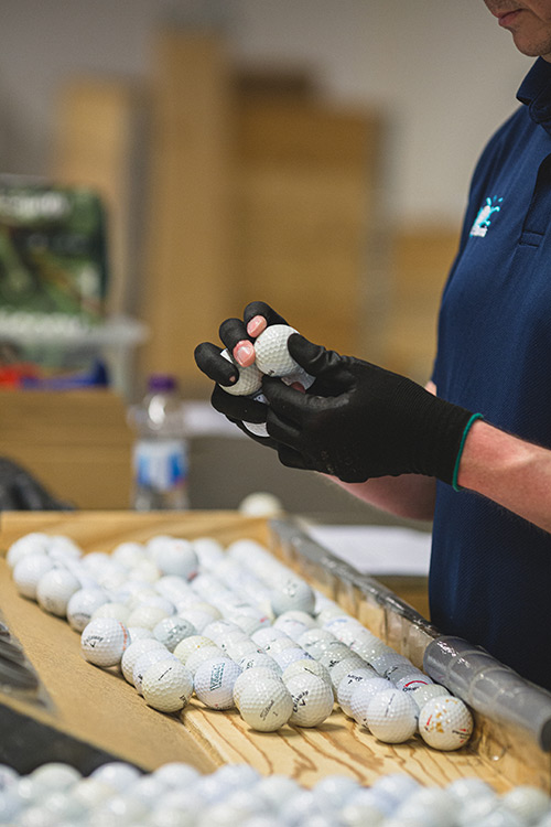 Hand med handske som sorterar golfbollar